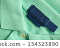 Blank blue laundry care clothes label on green shirt fabric texture background 134323890