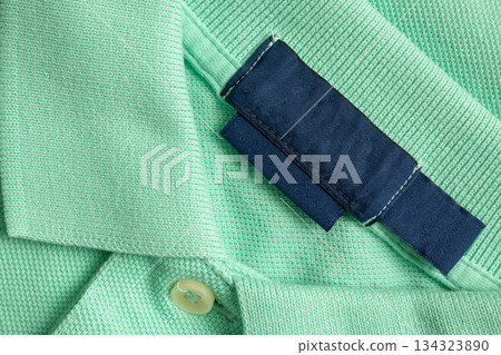 Blank blue laundry care clothes label on green shirt fabric texture background 134323890