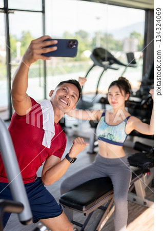 Fitness trainer coach man taking picture photo on phone with woman client after exercising in a gym 134324069
