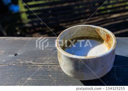 一杯烤綠茶拿鐵放在木桌上,沐浴在柔和的陽光中。 一杯烤綠茶拿鐵放在木桌上,沐浴在柔和的陽光中。 134325255