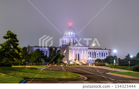 Night view of Oklahoma State Capitol in Oklahoma City. Neoclassical building features illuminated dome and columns amidst foggy atmosphere 134325444