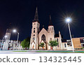 St. Mary's Catholic Church stands in downtown Lincoln, Nebraska, USA. Gothic Revival architecture features twin spires and a modern bell tower illuminated at night 134325445