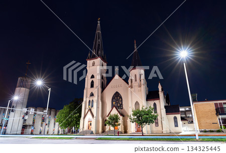 St. Mary's Catholic Church stands in downtown Lincoln, Nebraska, USA. Gothic Revival architecture features twin spires and a modern bell tower illuminated at night St. Mary's Catholic Church stands in downtown Lincoln, Nebraska, USA. Gothic Revival architecture features twin spires and a modern bell tower illuminated at night 134325445