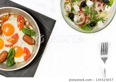 Fried eggs with sausages. Fresh salad and scrambled eggs. Healthy breakfast. 134325657