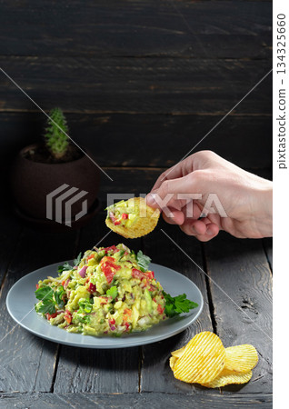 Eat a salad with chips. Mexican salad and chips. Hand and salad. 134325660