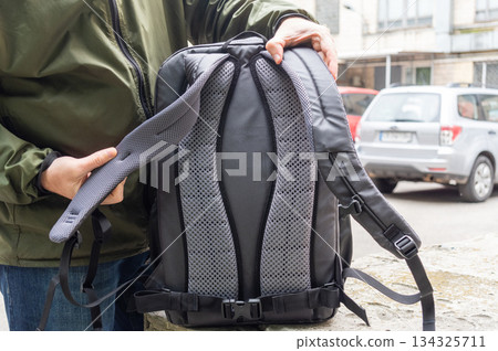 Man Demonstrating Backpack Back Panel and Straps. 134325711