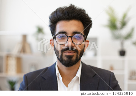 This portrait shows a handsome Indian man wearing glasses and a suit, looking directly at the camera This portrait shows a handsome Indian man wearing glasses and a suit, looking directly at the camera 134325910