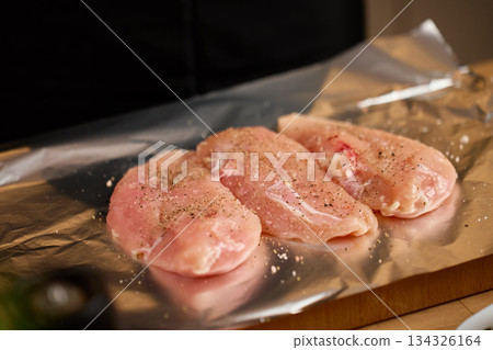 Raw chicken fillets seasoned with spices on foil for cooking preparation Raw chicken fillets seasoned with spices on foil for cooking preparation 134326164