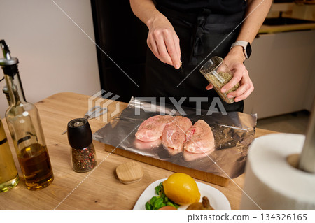Seasoning raw chicken with herbs on kitchen countertop Seasoning raw chicken with herbs on kitchen countertop 134326165