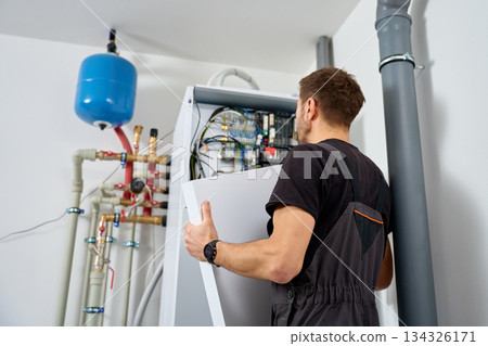 Technician open control unit to inspecting heat pump system in house 134326171