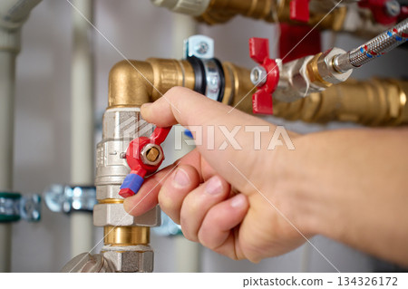 Technician adjusting valve on heat pump piping system close up Technician adjusting valve on heat pump piping system close up 134326172