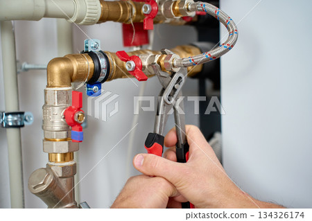 Hands tightening plumbing fitting with adjustable wrench 134326174
