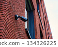 Surveillance camera mounted on a red brick wall exterior 134326225