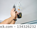 Man drilling ceiling with cordless power drill indoors 134326232