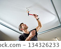 Man hammering nail-in anchor into ceiling 134326233