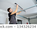 Man installing linear LED light fixture on ceiling indoors 134326234