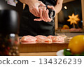 Woman seasoning raw chicken breast with salt grinder on foil 134326239