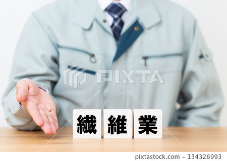 身穿工作服的中年男性商人，旁邊是一塊紡織工業的磚塊。 134326993