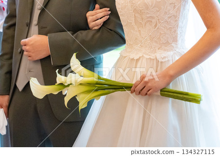 Bride holding lilies at wedding ceremony 134327115
