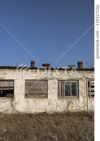 abandoned building made of brick and blue sky, an abandoned building intended for demolition, the entrances and windows to the building are boarded up 134327282