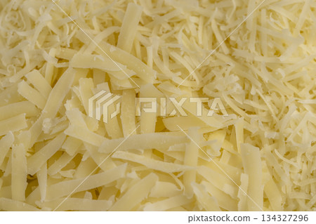 finely grated yellow cheese on a grater for pizza or pasta, yellow grated cheese with pieces for cooking various foods finely grated yellow cheese on a grater for pizza or pasta, yellow grated cheese with pieces for cooking various foods 134327296