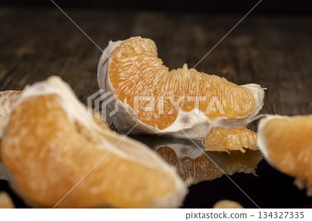 half of an orange citrus on a black mirror surface, ripe and sweet and juicy citrus is reflected on the black mirror, closeup half of an orange citrus on a black mirror surface, ripe and sweet and juicy citrus is reflected on the black mirror, closeup 134327335