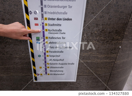 Berlin, Germany, August 10, 2023. Shot at Checkpoint Charlie subway station. A hand points to the train stop at the memorial on the information sign. Berlin, Germany, August 10, 2023. Shot at Checkpoint Charlie subway station. A hand points to the train stop at the memorial on the information sign. 134327880