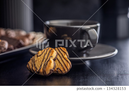 Heart shaped cookie and coffee cup on black table. Heart shaped cookie and coffee cup on black table. 134328153
