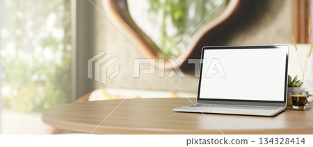 White screen laptop and coffee on wooden round table across door and window in a living room or cafe White screen laptop and coffee on wooden round table across door and window in a living room or cafe 134328414