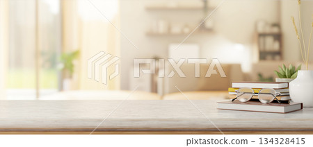 Eyeglasses over book aside vase and potted plants on marble counter table in a bright living room. Eyeglasses over book aside vase and potted plants on marble counter table in a bright living room. 134328415