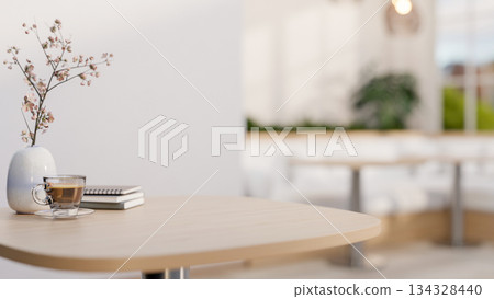 Coffee in glass cup and books aside flower vase on wooden stool table in a cosy cafe or coffee shop 134328440