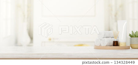 Towels with lotion and diffuser on wooden tray aside plant on marble counter in bright spa bathroom. 134328449