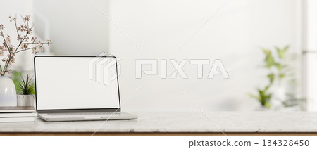 White screen laptop with books and potted plant on marble counter table in cafe with bright sunlight 134328450
