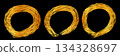 A single stroke of a gold-colored circle drawn with a brush on a black background 134328697