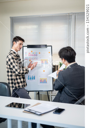 A man doing work presentation on white board and businessman boss reading document in company office 134329021