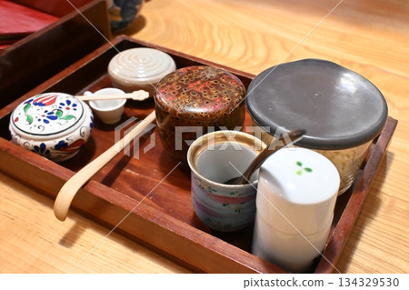 Ceramic condiment containers and wooden trays arranged on a Japanese dining table 134329530
