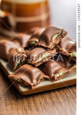 Chocolate bar with pistachios cream on plate on wooden table. Chocolate bar with pistachios cream on plate on wooden table. 134329587