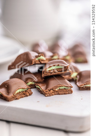 Chocolate bar with pistachios cream on white table. Chocolate bar with pistachios cream on white table. 134329592