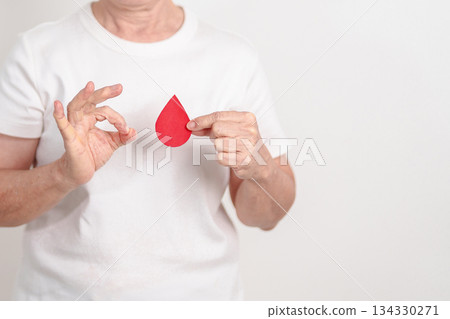 Elderly woman with red Blood drop paper for concept of June World Blood Donor day, Donation, January Blood donor awareness month, April Hemophilia awareness day, May Thalassemia Day, Anemia awareness 134330271
