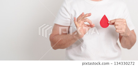 Elderly woman with red Blood drop paper for concept of June World Blood Donor day, Donation, January Blood donor awareness month, April Hemophilia awareness day, May Thalassemia Day, Anemia awareness Elderly woman with red Blood drop paper for concept of June World Blood Donor day, Donation, January Blood donor awareness month, April Hemophilia awareness day, May Thalassemia Day, Anemia awareness 134330272