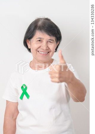 Elderly with Green Ribbon for concept of July Eye Injury Prevention month, January Glaucoma Awareness month, February Gallbladder and Bile duct and October Liver cancer. Health and world cancer day Elderly with Green Ribbon for concept of July Eye Injury Prevention month, January Glaucoma Awareness month, February Gallbladder and Bile duct and October Liver cancer. Health and world cancer day 134330286