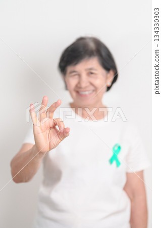Elderly with Teal Ribbon for September Ovarian Cancer Awareness month, PCOS, January Cervical Cancer, April Sexual Assault, June PSTD, Post Traumatic Stress Disorder, May Tourette syndrome 134330303