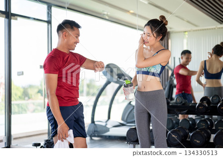 Fitness trainer coach man looking at watch checking time aside woman client after exercising in gym. 134330513