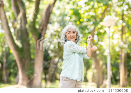 Old age asian woman grandmother crossing both arms stretching while warming up or exercising in park Old age asian woman grandmother crossing both arms stretching while warming up or exercising in park 134330608