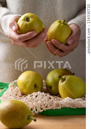 Fresh pear in mesh bag holding by woman hand Fresh pear in mesh bag holding by woman hand 134330720