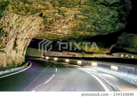 The Mas d'Azil Cave in France features a grand entrance surrounded by lush greenery. 134330896