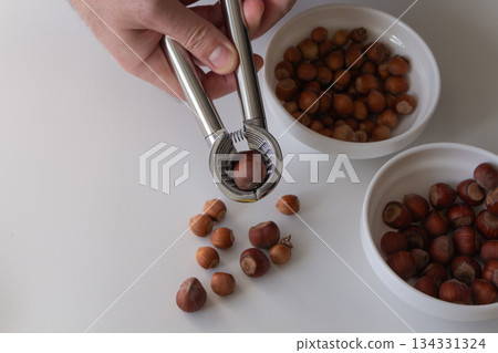 Man cracking hazelnuts two varieties Man cracking hazelnuts two varieties 134331324