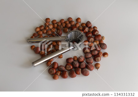 Scattering of nuts next to a nutcracker on a light background Scattering of nuts next to a nutcracker on a light background 134331332