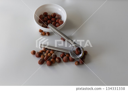 The nutcracker lies on the nuts, next to the plate with hazelnuts The nutcracker lies on the nuts, next to the plate with hazelnuts 134331338