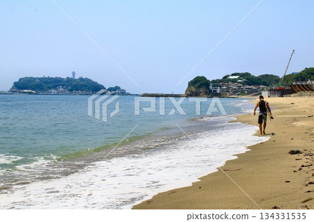 A surfer walking on the beach overlooking Enoshima 134331535